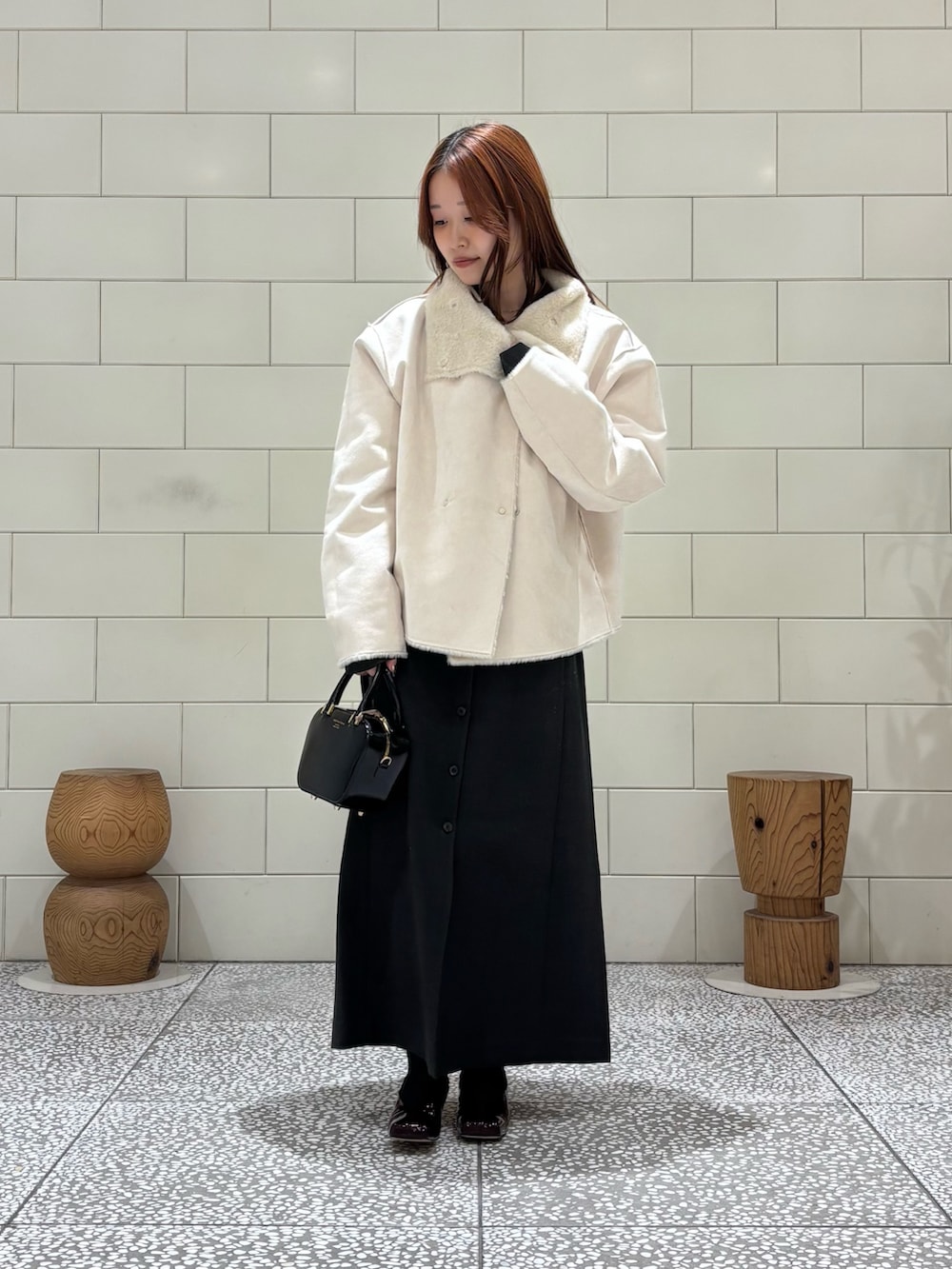 グレー系のワンピース、ホワイト系のブルゾン、ブラック系のショルダーバッグを着用したレディースの冬コーディネートの2枚目の写真