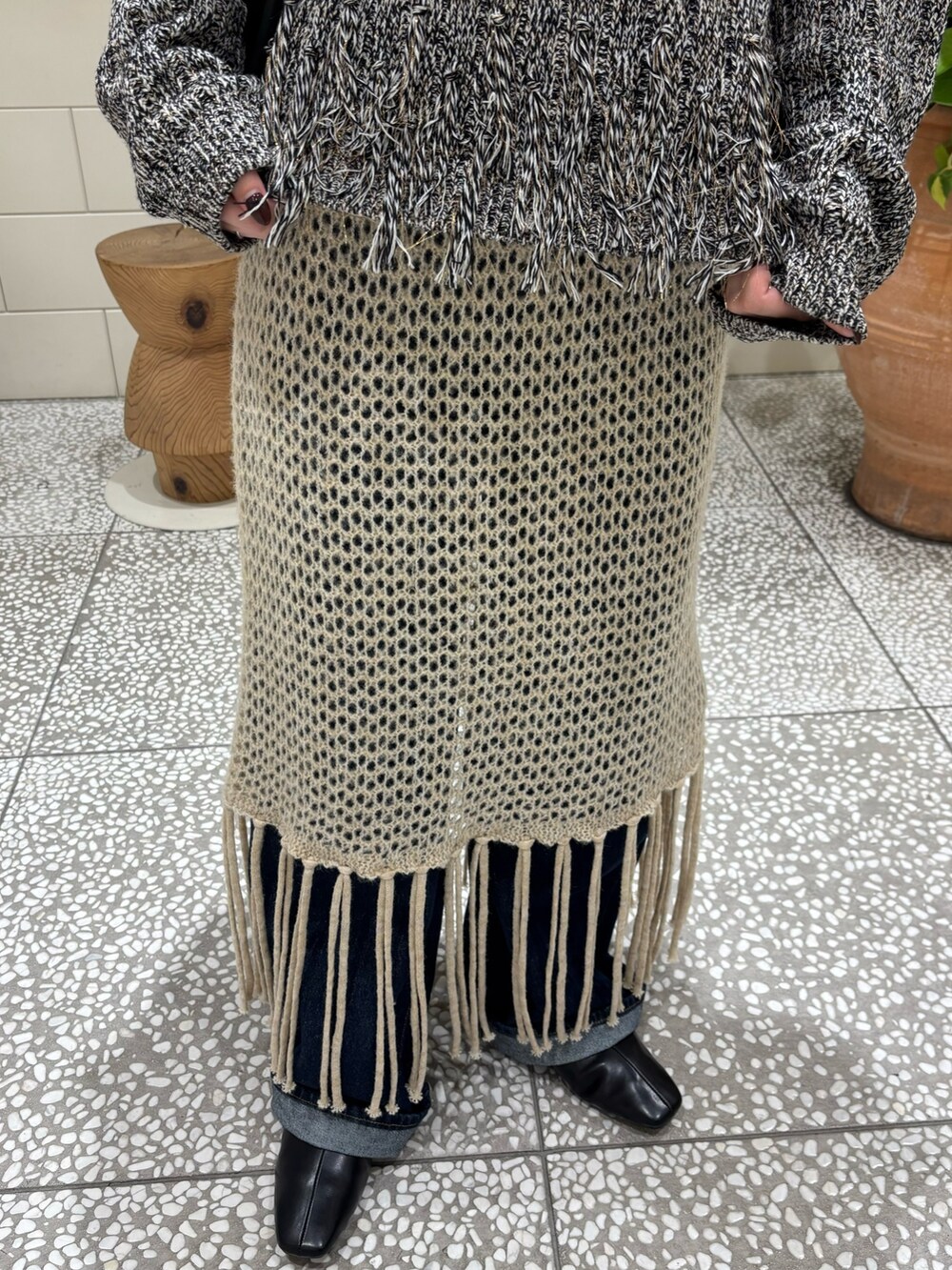 ブラック系のニット/セーター、ブルー系のデニムパンツ、ブラック系のブーツを着用したレディースの秋コーディネートの6枚目の写真