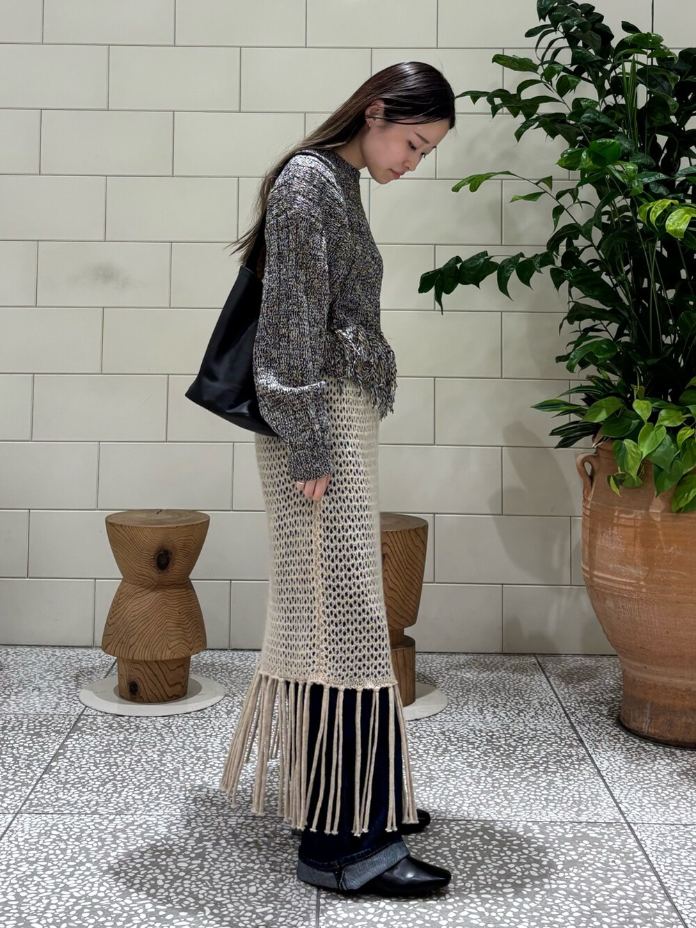 ブラック系のニット/セーター、ブルー系のデニムパンツ、ブラック系のブーツを着用したレディースの秋コーディネートの2枚目の写真