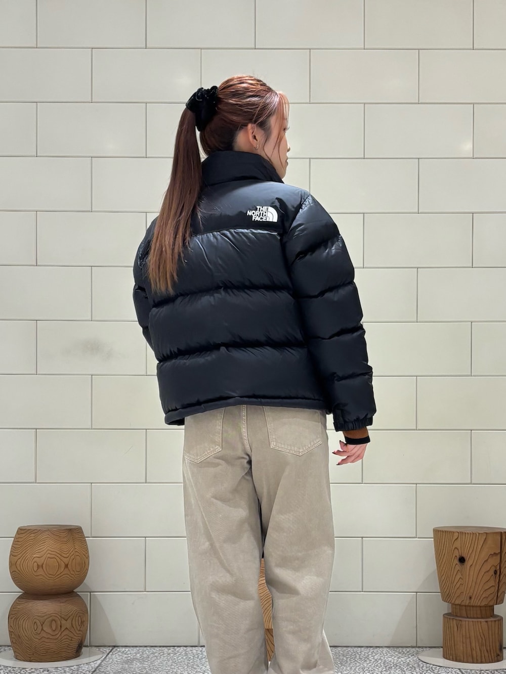 ブラウン系のニット/セーター、ブラック系のダウンジャケット/コート、ベージュ系のデニムパンツを着用したレディースの秋コーディネートの4枚目の写真