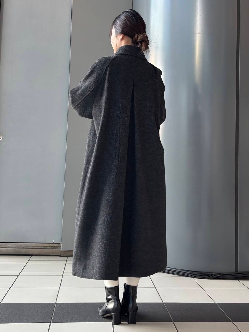 ブラック系のステンカラーコート、ホワイト系のショルダーバッグ、ブラウン系のスカートを着用したレディースの冬コーディネートの3枚目の写真