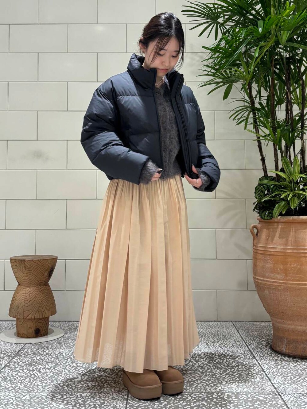 イエロー系のスカート、ブラウン系のカーディガン/ボレロ、ブラウン系のブーツを着用したレディースの冬コーディネートの2枚目の写真