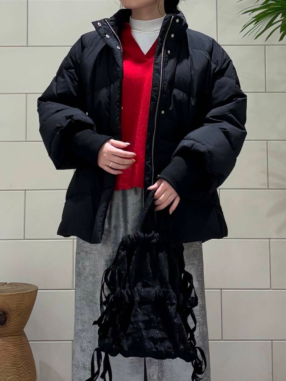 ブラック系のダウンジャケット/コート、シルバー系のスカート、レッド系のニット/セーターを着用したレディースの冬コーディネートの6枚目の写真