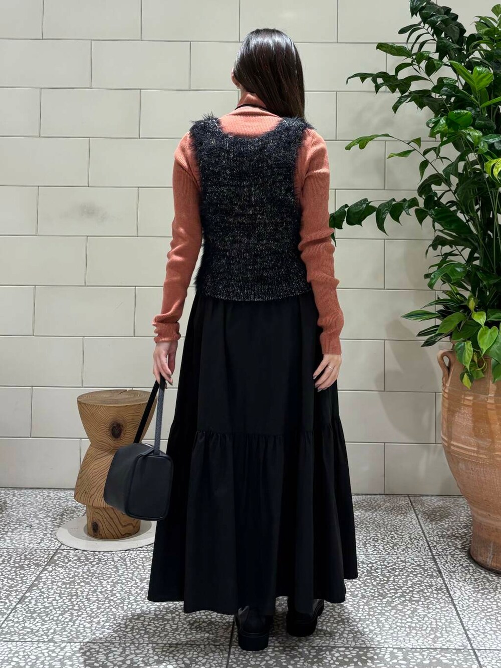 ブラック系のスカート、ブラック系のハンドバッグ、オレンジ系のニット/セーターを着用したレディースの秋コーディネートの4枚目の写真