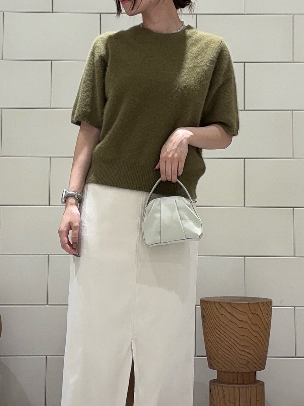 グリーン系のニット/セーター、ホワイト系のスカート、ホワイト系のハンドバッグを着用したレディースの夏コーディネートの2枚目の写真