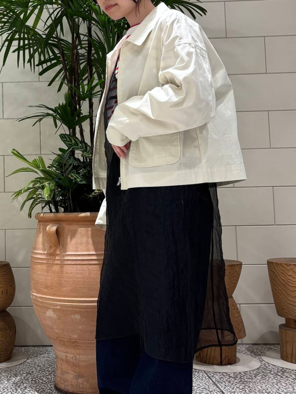 ホワイト系のスニーカー、ブラック系のワンピース、ブルー系のデニムパンツを着用したレディースの冬コーディネートの6枚目の写真