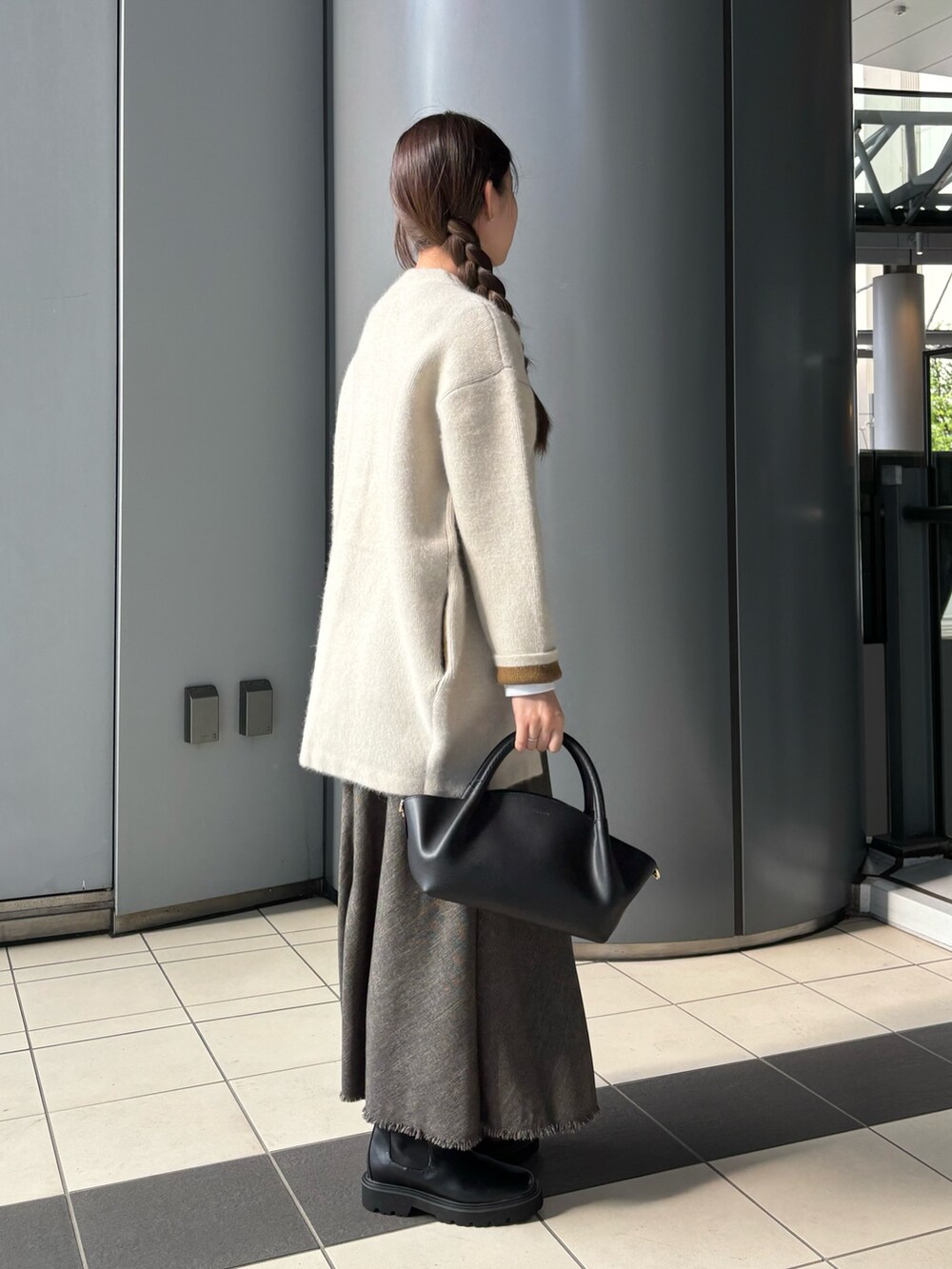 ブラウン系のワンピース、ブラック系のショルダーバッグ、ホワイト系のTシャツ/カットソーを着用したレディースの秋コーディネートの2枚目の写真