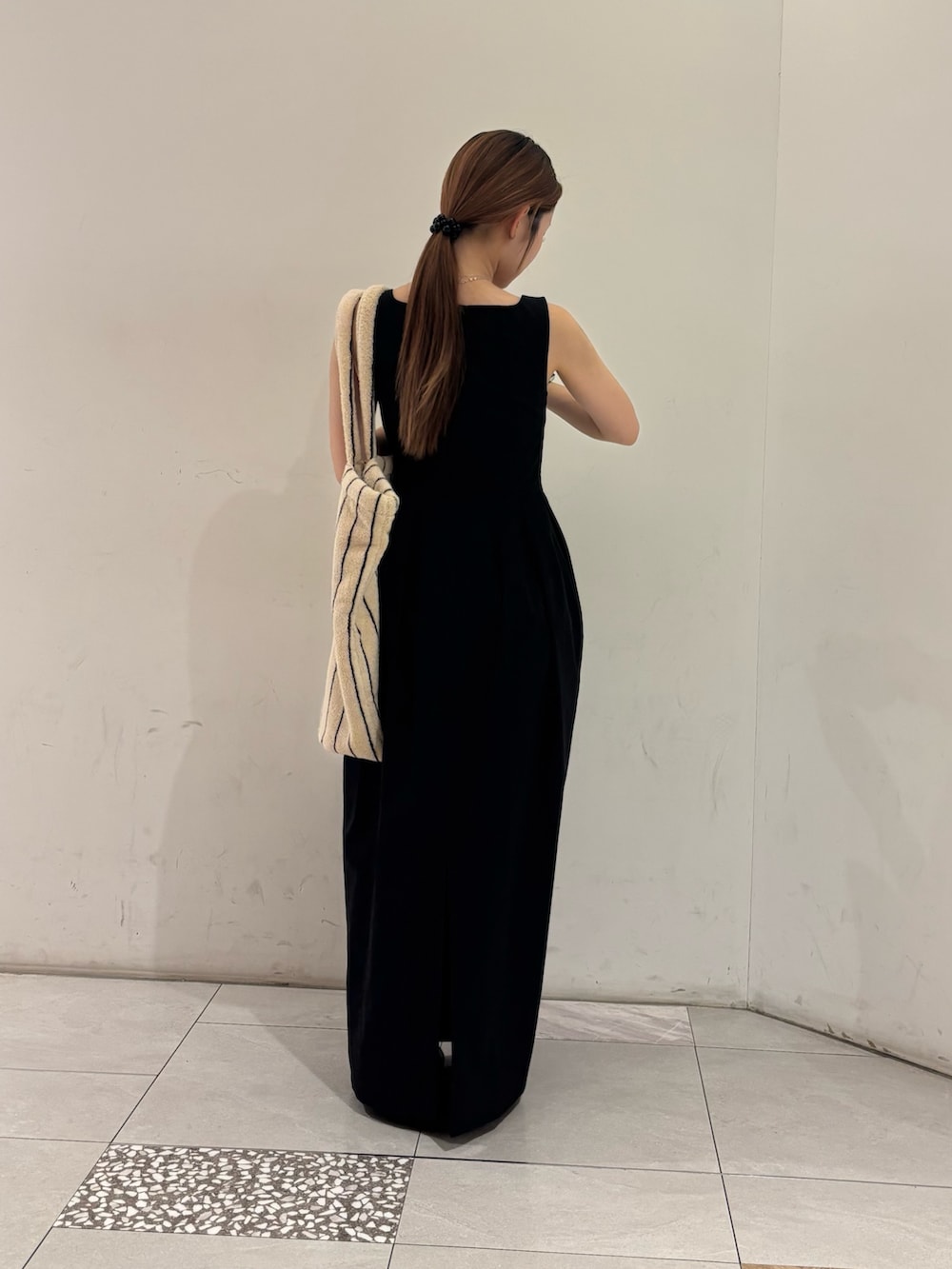 ブラック系のワンピース、ホワイト系のトートバッグ、ブラック系のヘアゴムを着用したレディースの夏コーディネートの3枚目の写真