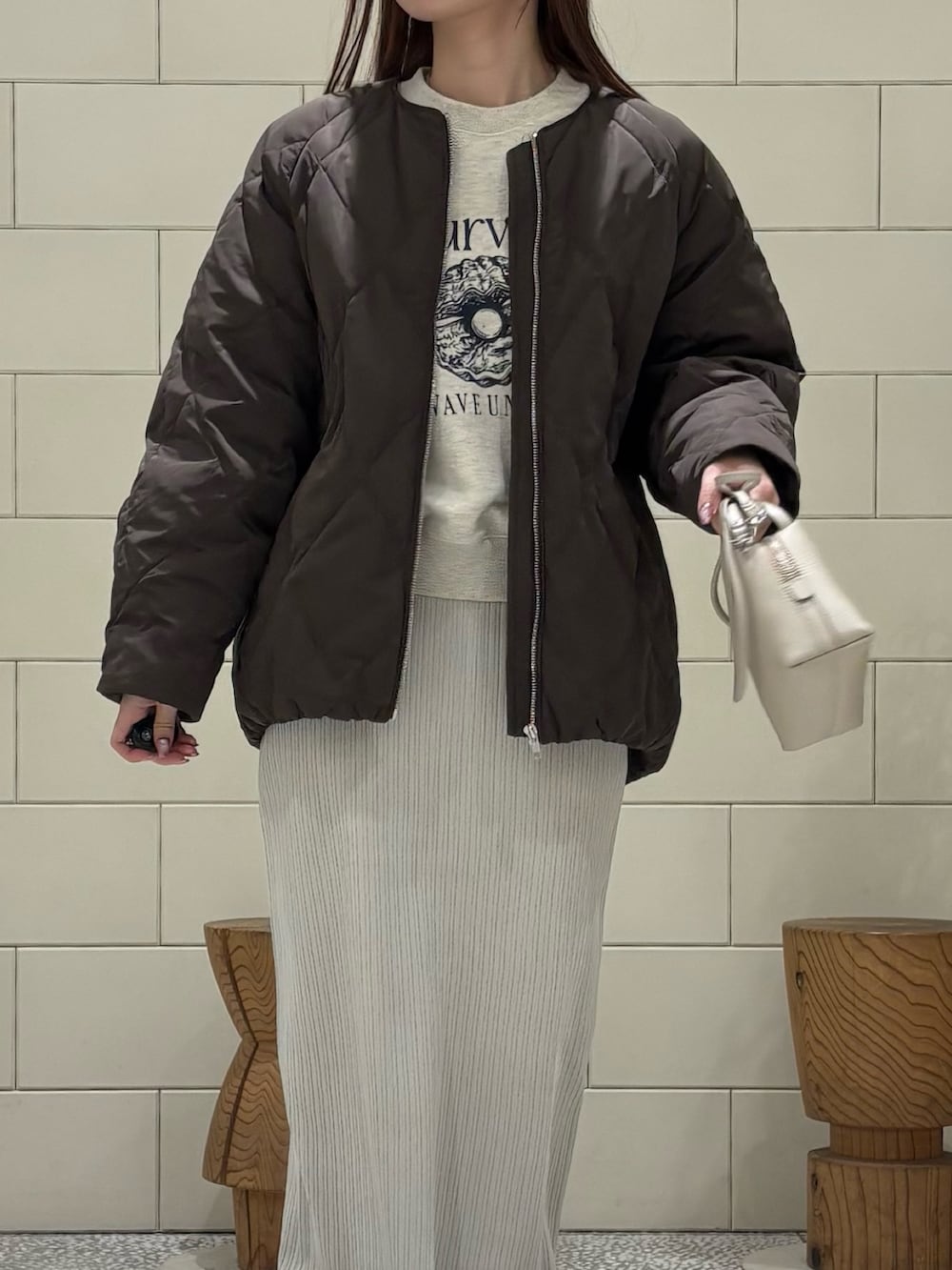 ベージュ系のスウェット、ブラウン系のダウンジャケット/コート、ベージュ系のスカートを着用したレディースの冬コーディネートの3枚目の写真