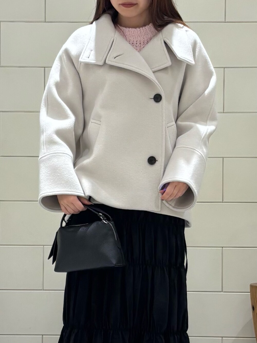 ピンク系のニット/セーター、ブラック系のスカート、ホワイト系のその他アウターを着用したレディースの冬コーディネートの6枚目の写真