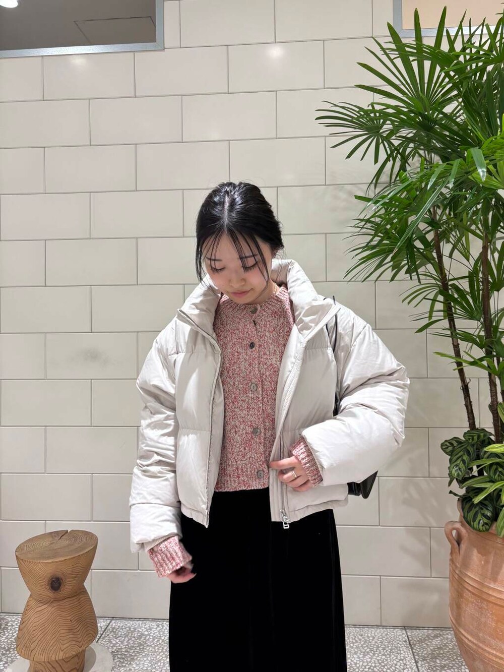 ブラック系のスカート、ベージュ系のカーディガン/ボレロ、ホワイト系のダウンジャケット/コートを着用したレディースの冬コーディネートの2枚目の写真