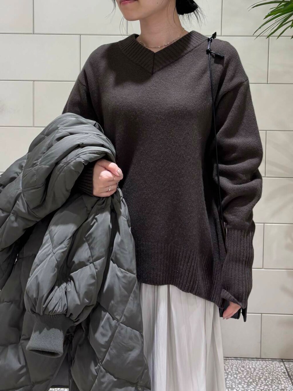 ブラウン系のニット/セーター、ホワイト系のスカート、グレー系のダウンジャケット/コートを着用したレディースの冬コーディネートの6枚目の写真