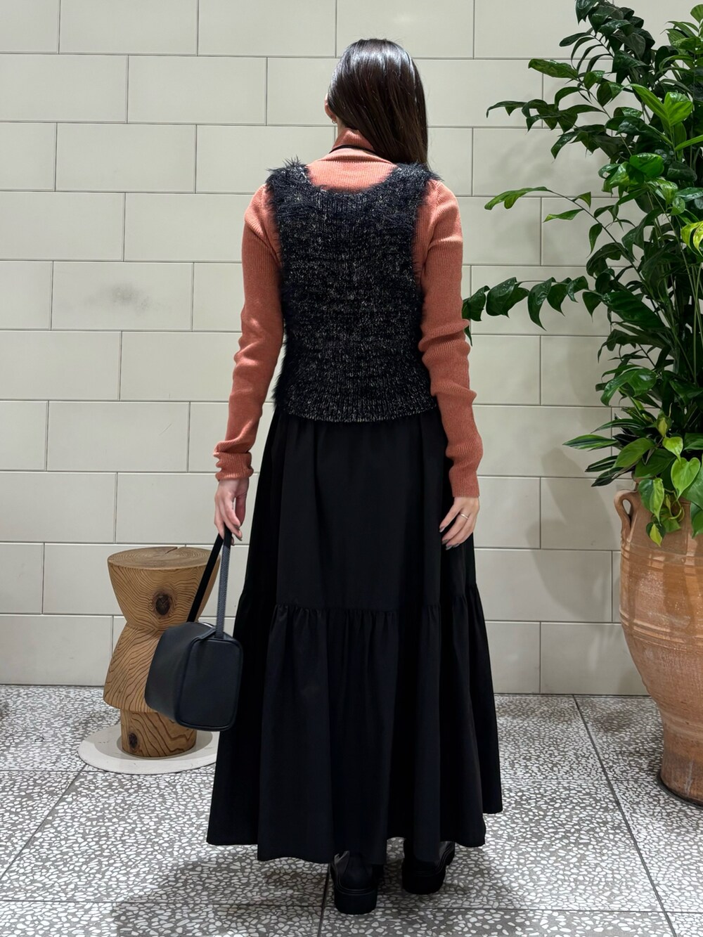 オレンジ系のニット/セーター、ブラック系のベスト、ブラック系のハンドバッグを着用したレディースの秋コーディネートの4枚目の写真