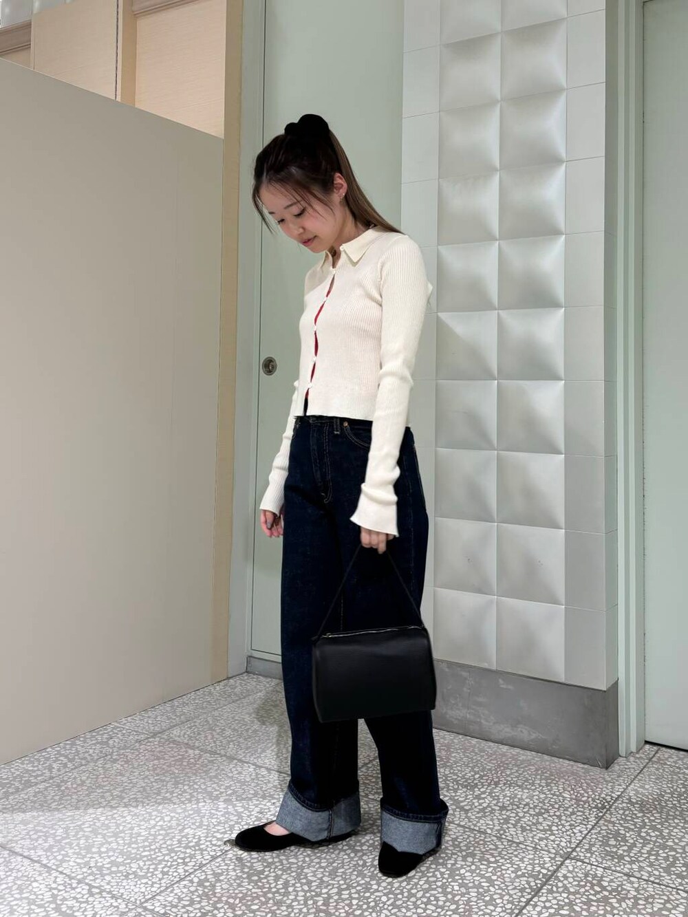 ブルー系のデニムパンツ、オレンジ系のタンクトップ、ブラック系のハンドバッグを着用したレディースの夏コーディネートの3枚目の写真