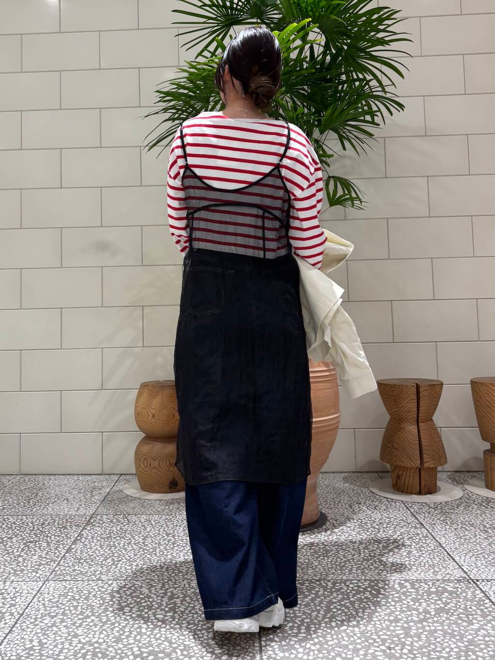 ホワイト系のスニーカー、ブラック系のワンピース、ブルー系のデニムパンツを着用したレディースの冬コーディネートの4枚目の写真