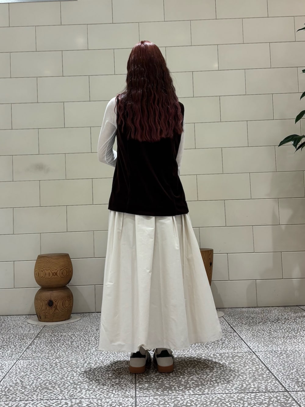 ホワイト系のTシャツ/カットソー、ブラウン系のベスト、ホワイト系のスカートを着用したレディースの秋コーディネートの2枚目の写真