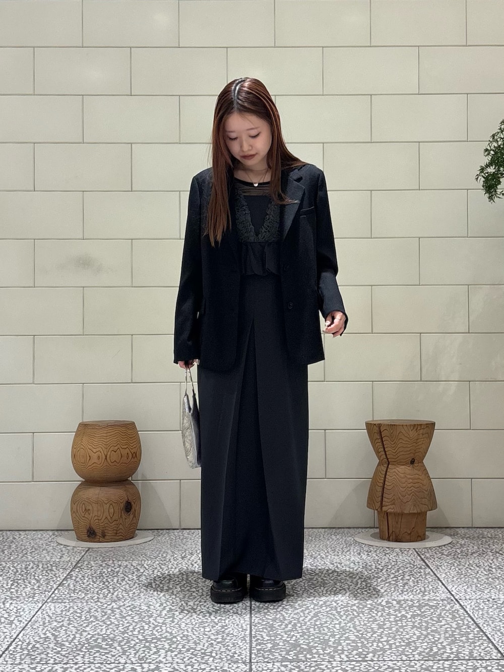 グレー系のドレス、ブラック系のテーラードジャケット、シルバー系のハンドバッグを着用したレディースの春コーディネートの2枚目の写真