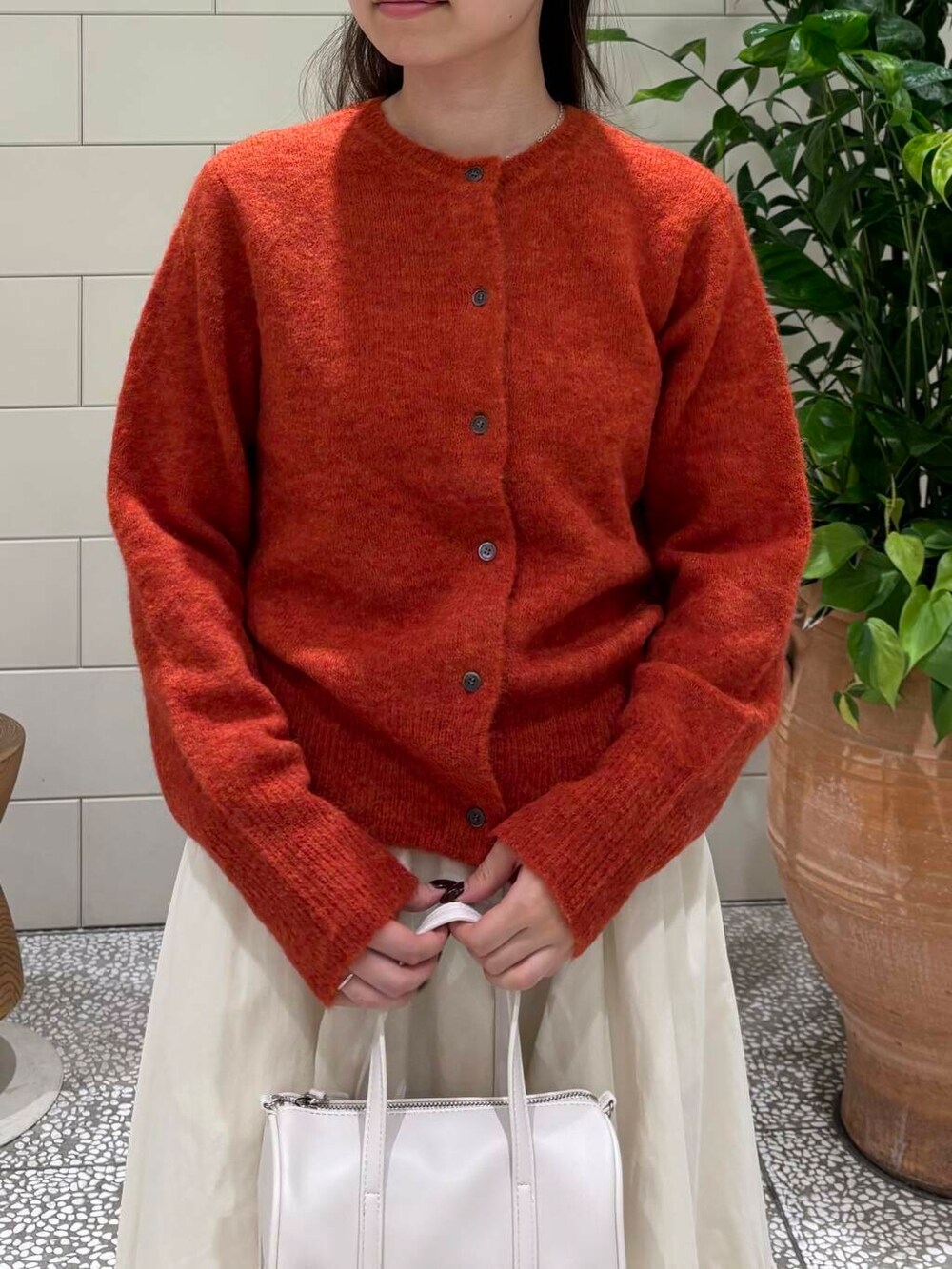 ホワイト系のスカート、ホワイト系のボストンバッグ、ブラック系のブーツを着用したレディースの秋コーディネートの5枚目の写真