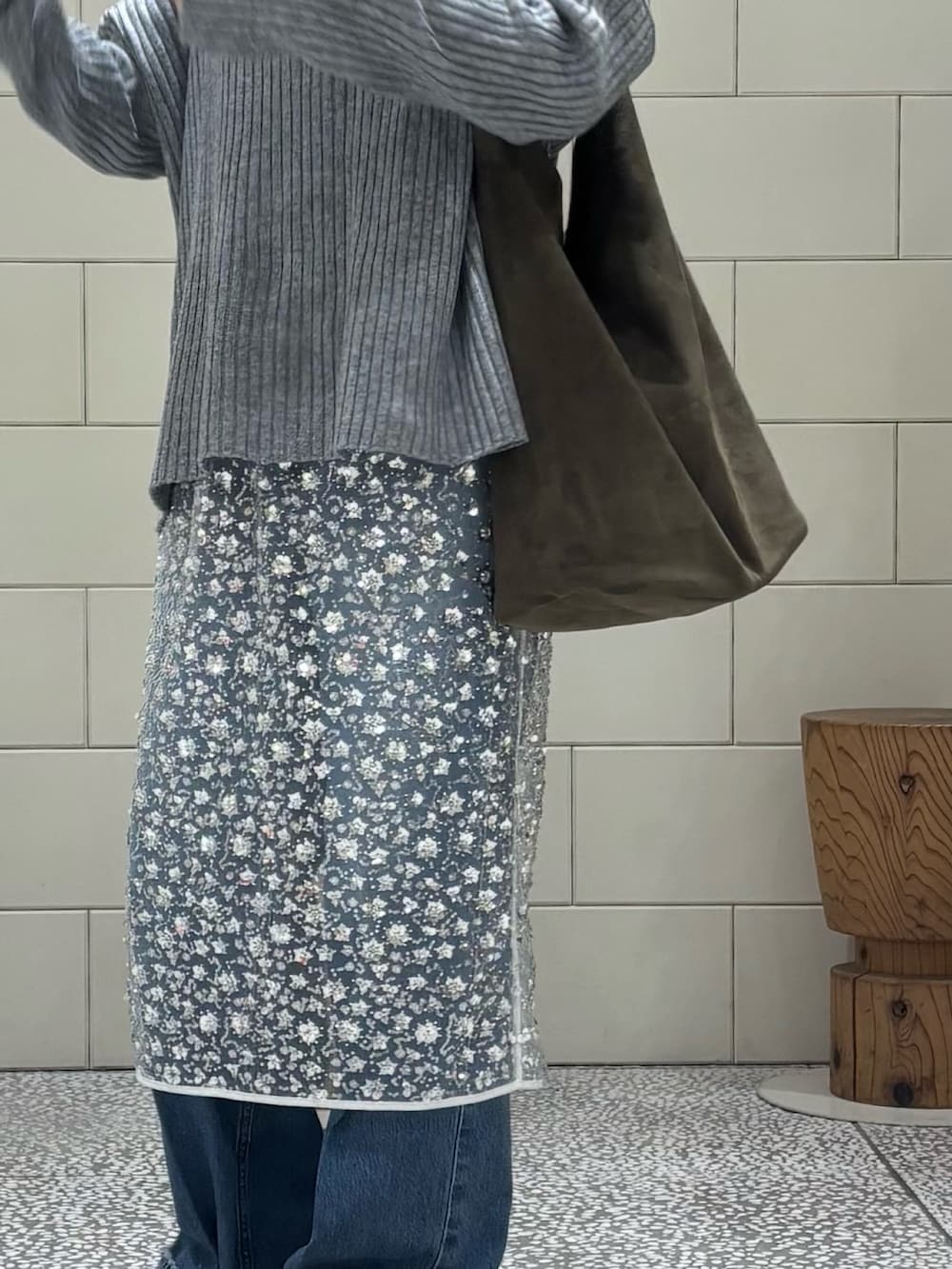 グレー系のニット/セーター、ホワイト系のスカート、ブルー系のデニムパンツを着用したレディースの冬コーディネートの4枚目の写真