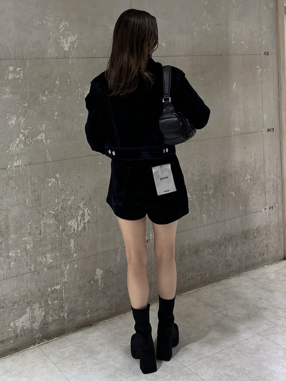 ブラック系のショルダーバッグ、ブラック系のブーツ、ブルー系のブルゾンを着用したレディースの秋コーディネートの4枚目の写真