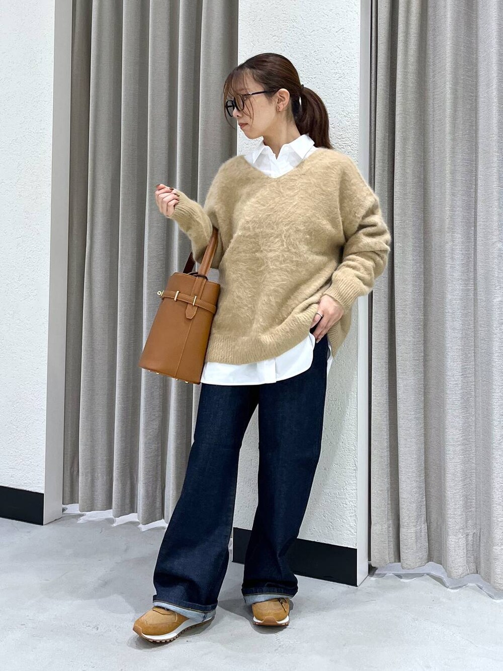 ブルー系のデニムパンツ、ベージュ系のニット/セーター、ホワイト系のシャツ/ブラウスを着用したレディースの秋コーディネートの5枚目の写真