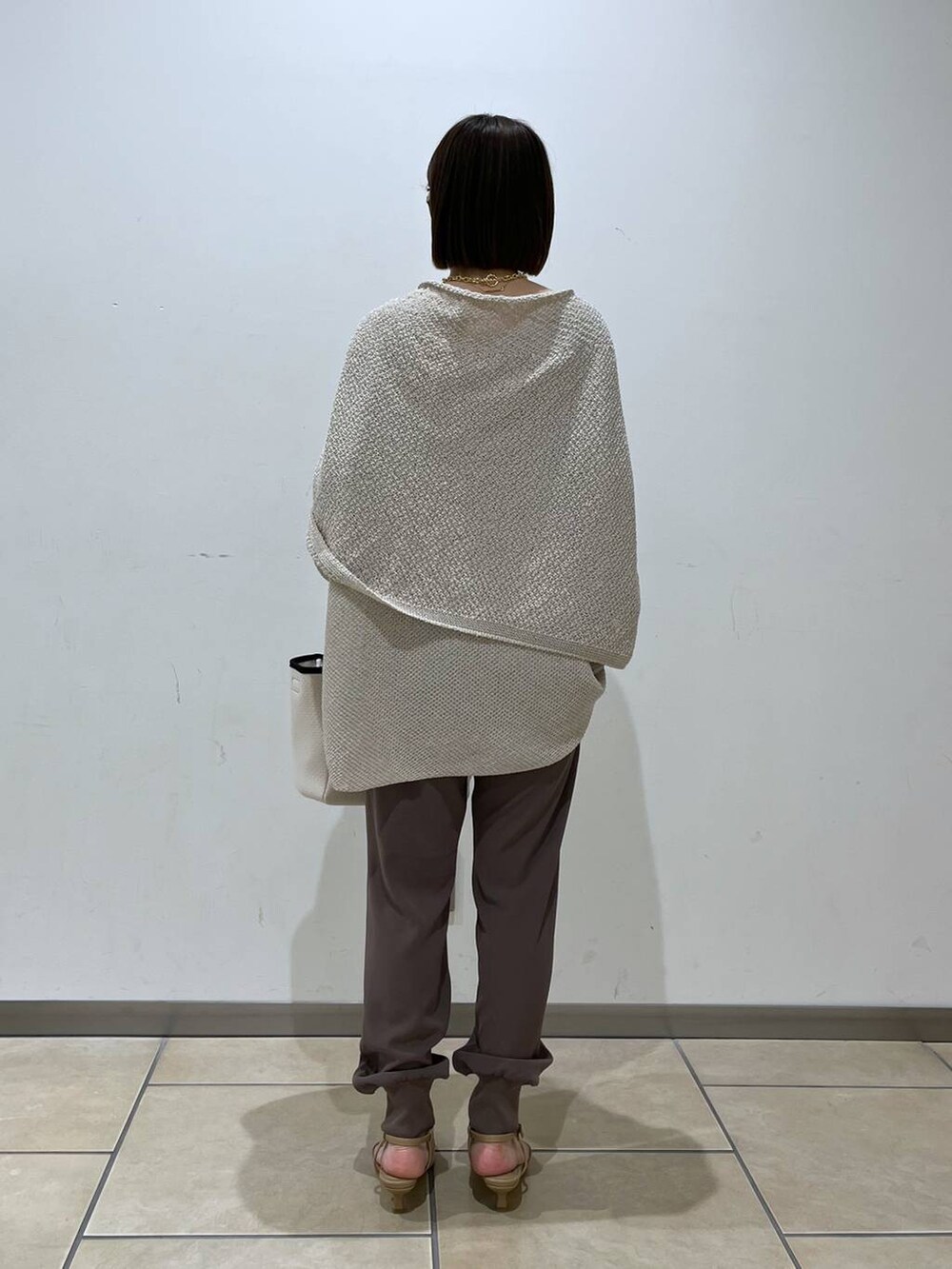 ベージュ系のニット/セーター、ベージュ系のパンプス、ホワイト系のトートバッグを着用したレディースの春コーディネートの3枚目の写真