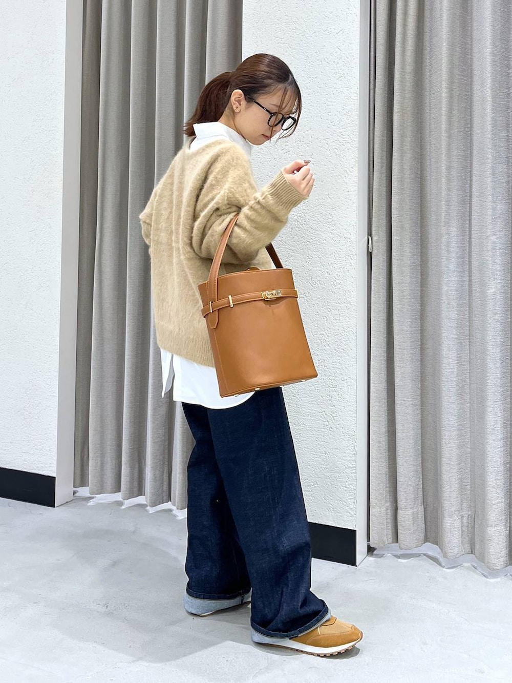 ブルー系のデニムパンツ、ベージュ系のニット/セーター、ホワイト系のシャツ/ブラウスを着用したレディースの秋コーディネートの2枚目の写真