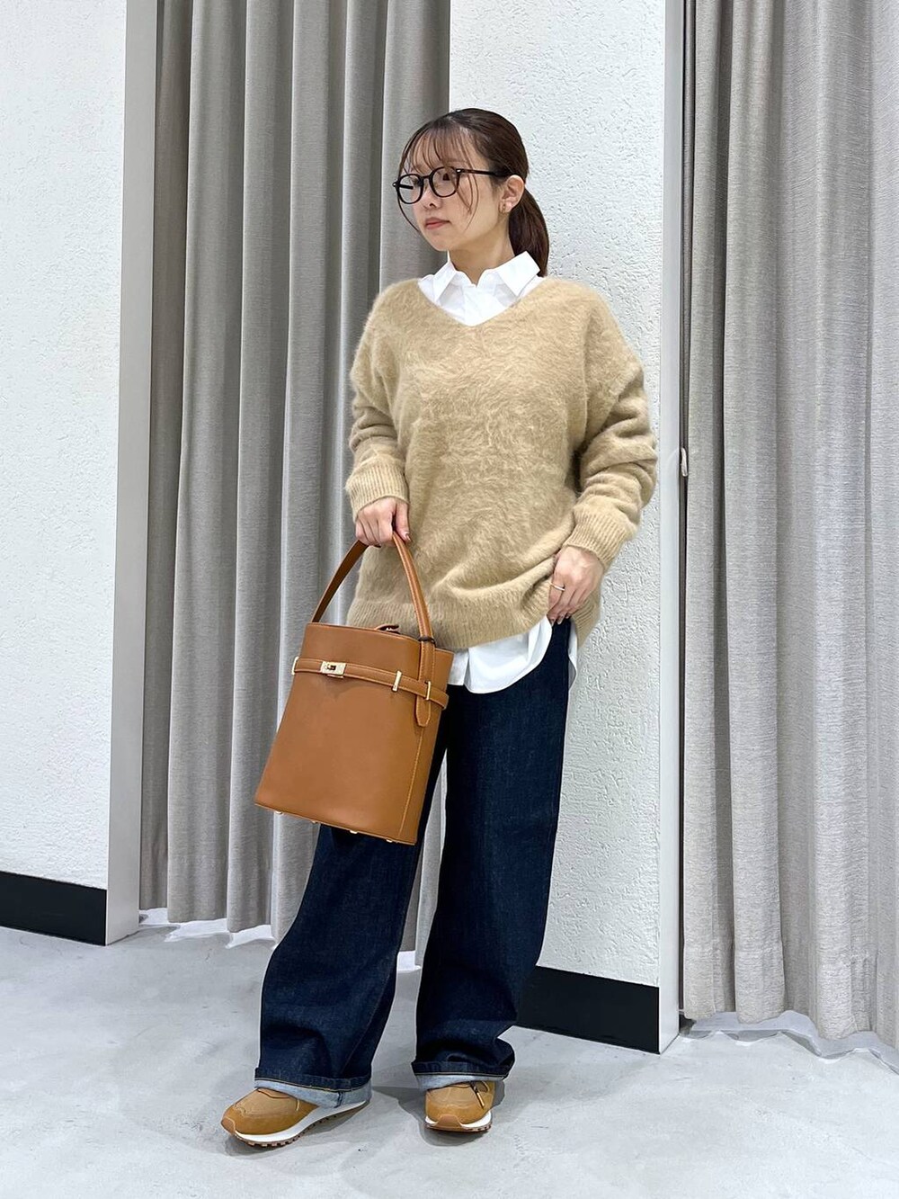 ブルー系のデニムパンツ、ベージュ系のニット/セーター、ホワイト系のシャツ/ブラウスを着用したレディースの秋コーディネートの4枚目の写真