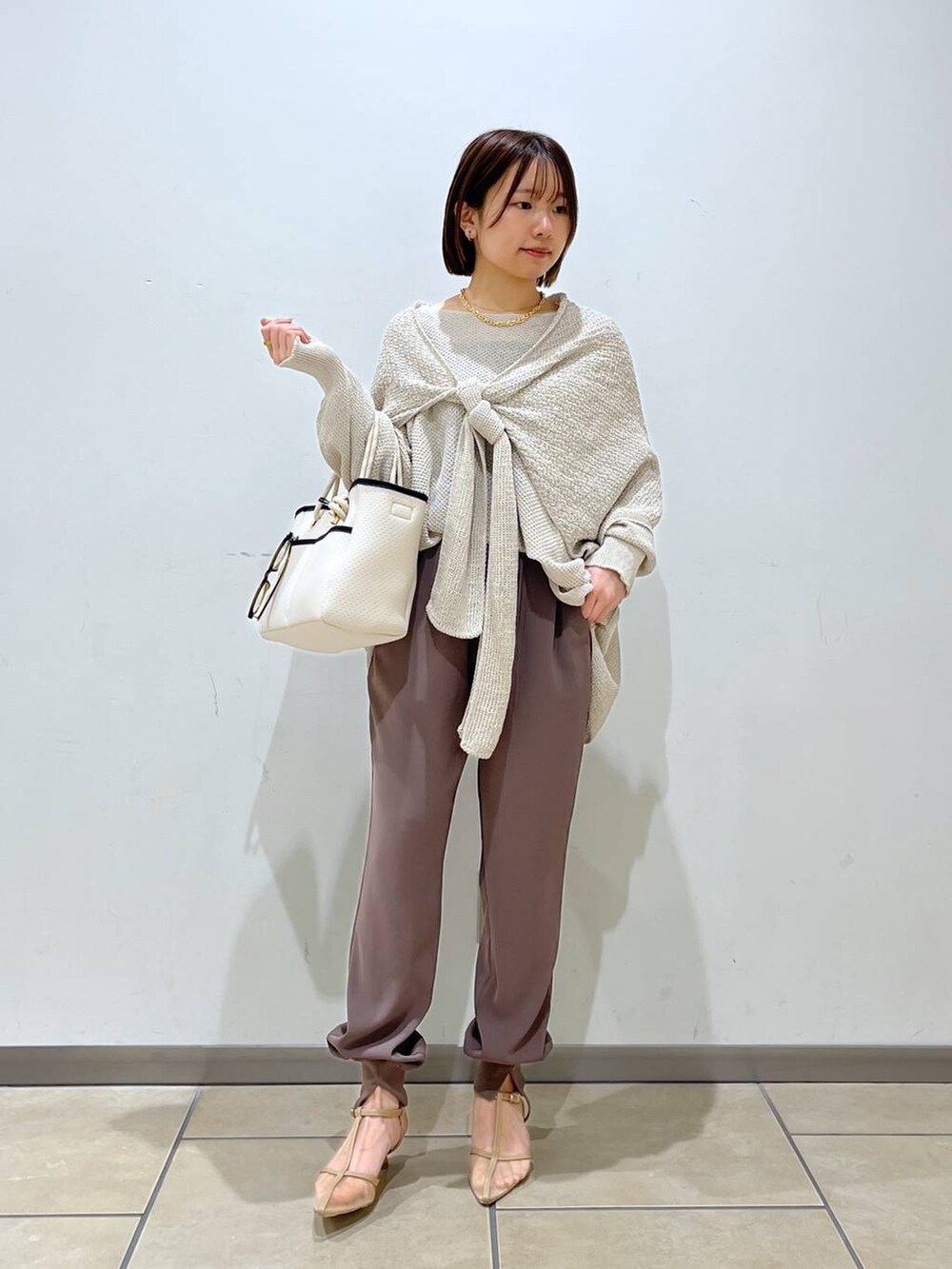 ベージュ系のニット/セーター、ベージュ系のパンプス、ホワイト系のトートバッグを着用したレディースの春コーディネートの5枚目の写真