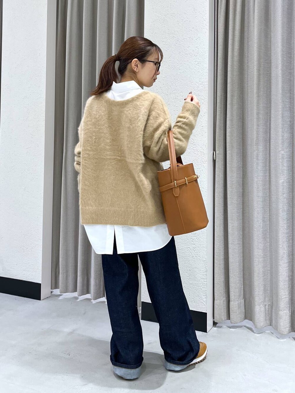 ブルー系のデニムパンツ、ベージュ系のニット/セーター、ホワイト系のシャツ/ブラウスを着用したレディースの秋コーディネートの3枚目の写真