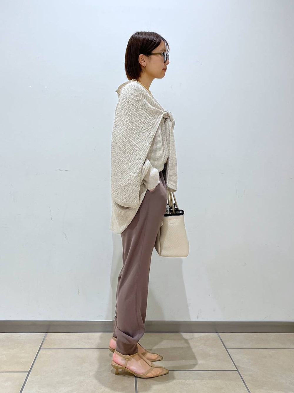 ベージュ系のニット/セーター、ベージュ系のパンプス、ホワイト系のトートバッグを着用したレディースの春コーディネートの2枚目の写真