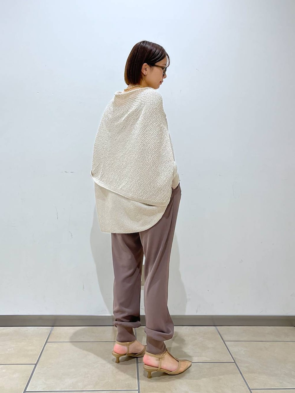 ベージュ系のニット/セーター、ベージュ系のパンプス、ホワイト系のトートバッグを着用したレディースの春コーディネートの4枚目の写真