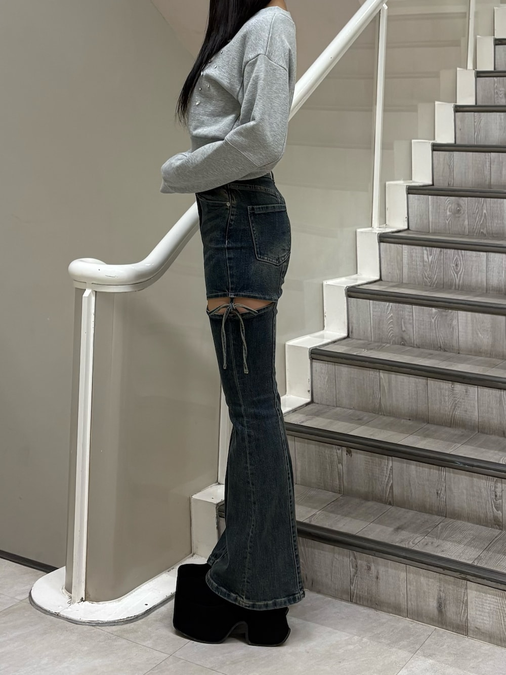 グレー系のスウェット、ブルー系のデニムパンツ、ブラック系のブーツを着用したレディースの冬コーディネートの2枚目の写真