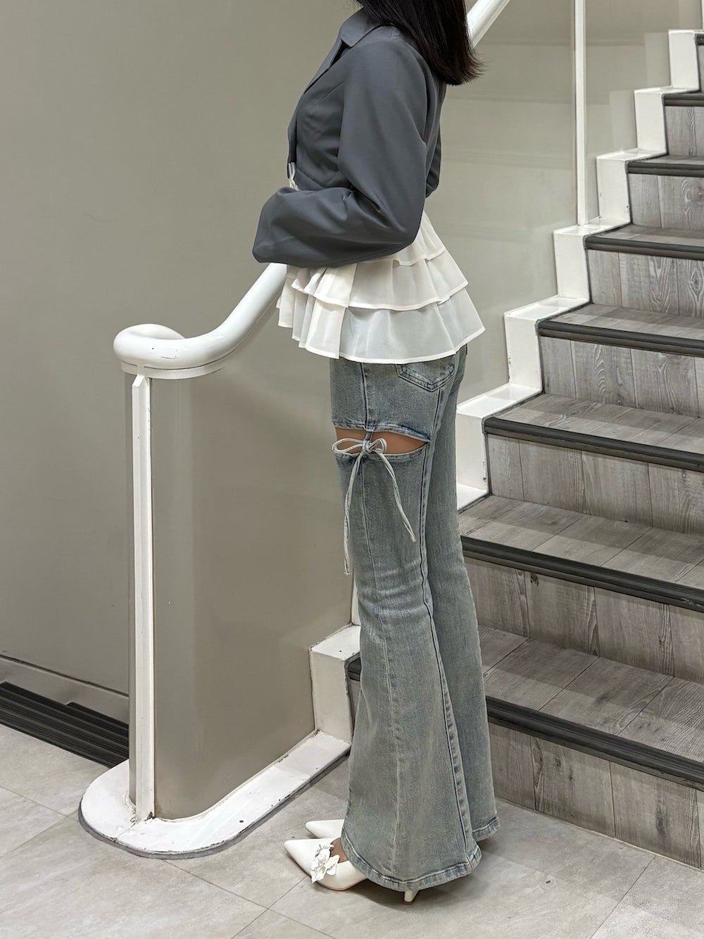 グレー系のその他アウター、ブルー系のデニムパンツ、ホワイト系のパンプスを着用したレディースの春コーディネートの2枚目の写真