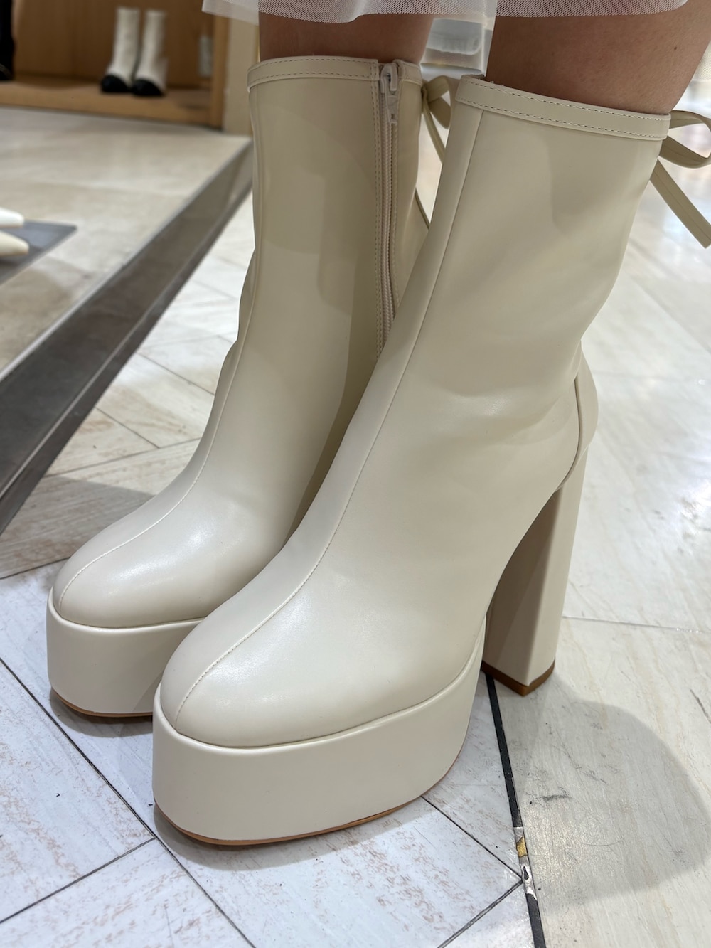 ホワイト系のニット/セーター、ブルー系のスカート、ホワイト系のブーツを着用したレディースの春コーディネートの5枚目の写真