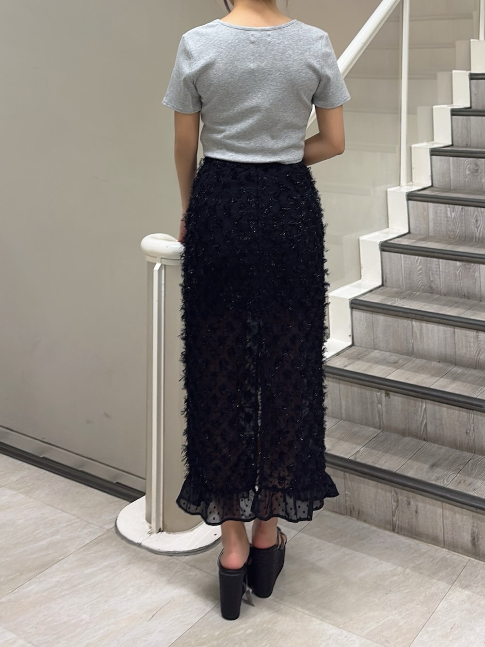 グレー系のTシャツ/カットソー、ブラック系のスカート、ブラック系のサンダルを着用したレディースの春コーディネートの3枚目の写真
