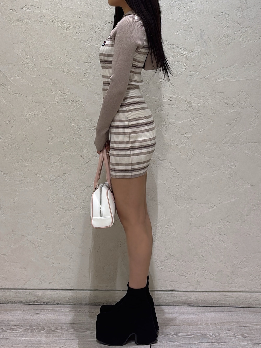 ベージュ系のワンピース、ピンク系のボストンバッグ、ブラック系のブーツを着用したレディースの冬コーディネートの2枚目の写真