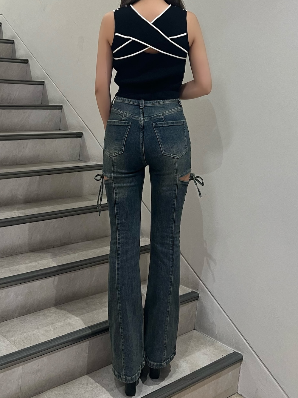 ブルー系のデニムパンツ、ブラック系のタンクトップ、ブラック系のサンダルを着用したレディースの夏コーディネートの3枚目の写真