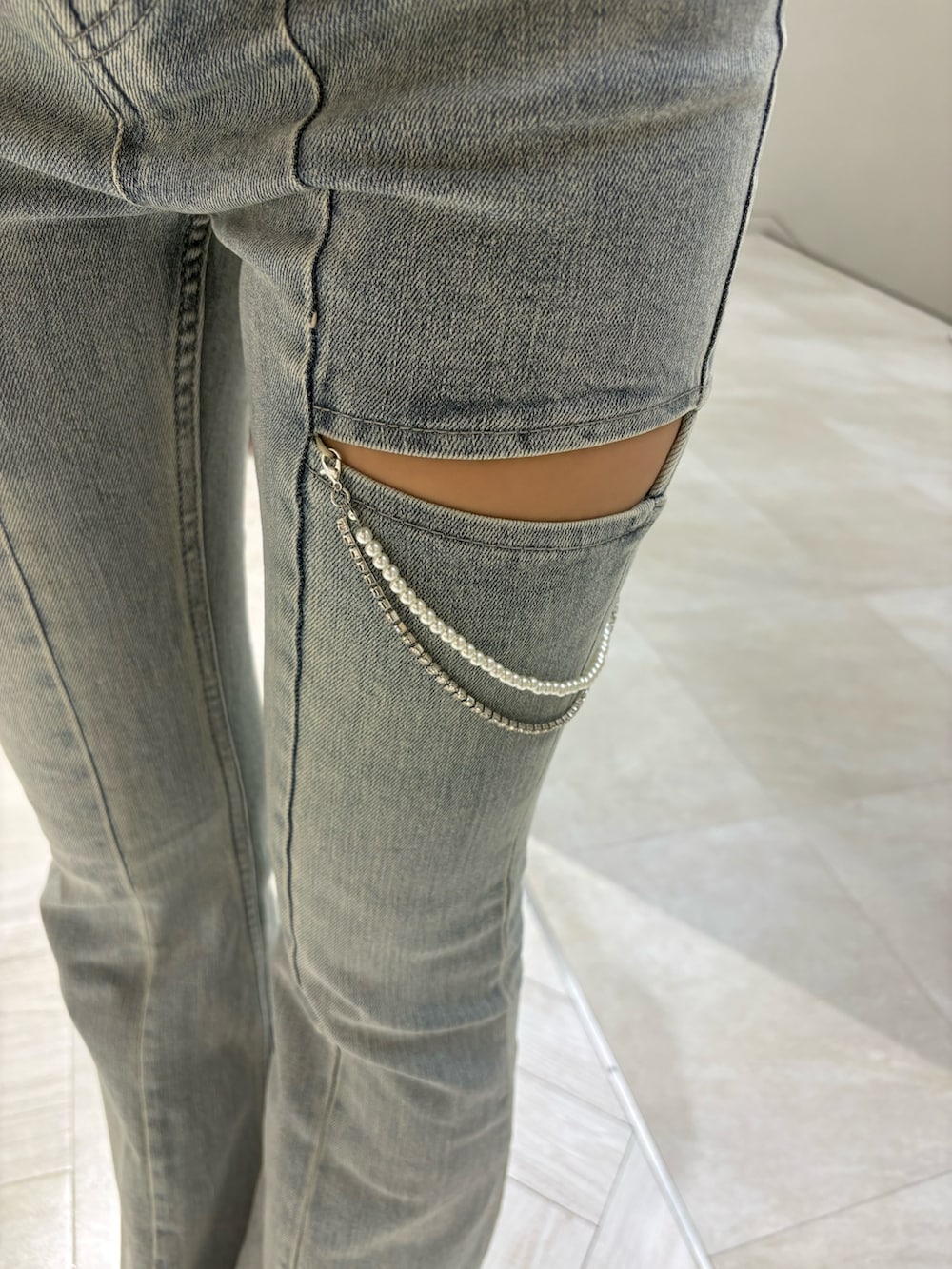 グレー系のニット/セーター、ブルー系のデニムパンツ、ホワイト系のサンダルを着用したレディースの夏コーディネートの5枚目の写真