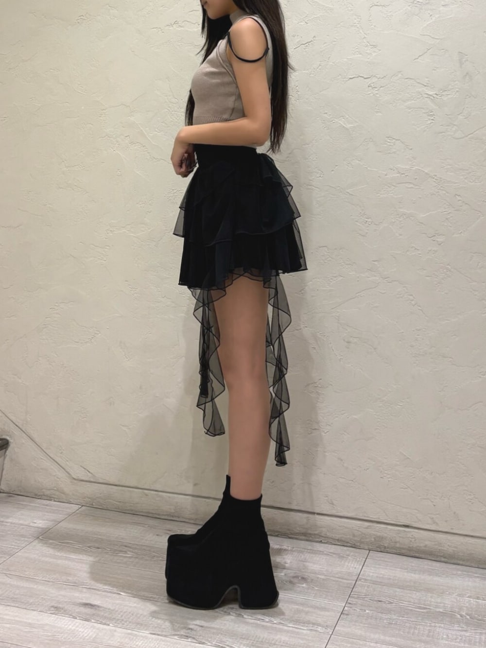 ブラック系のブーツ、ベージュ系のニット/セーター、ブラック系のスカートを着用したレディースの夏コーディネートの2枚目の写真