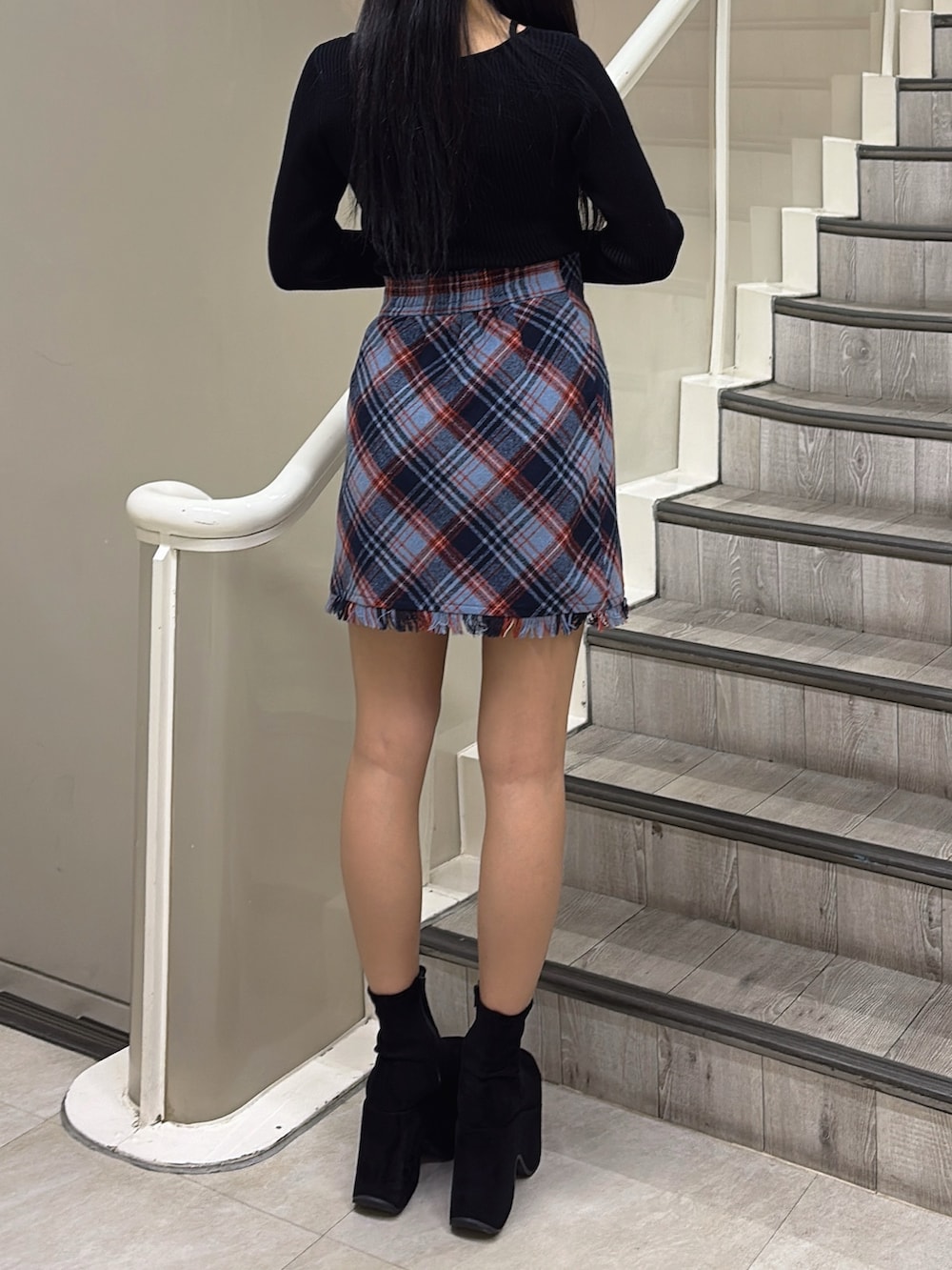 ブラック系のブルゾン、ブルー系のスカート、ブラック系のニット/セーターを着用したレディースの冬コーディネートの5枚目の写真