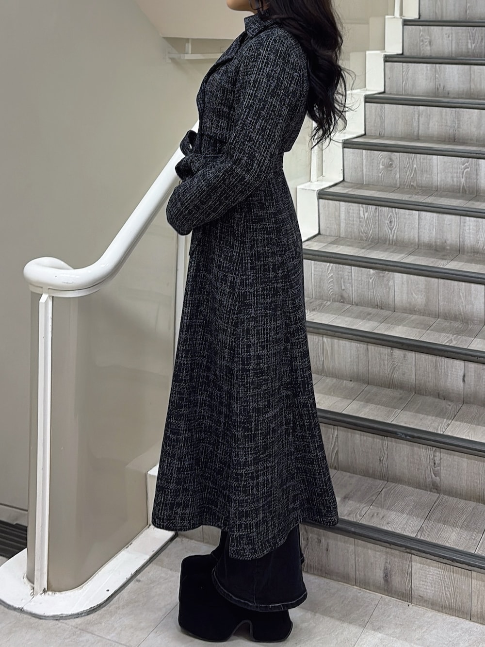 ブラック系のトレンチコート、ブラック系のブーツを着用したレディースの冬コーディネートの2枚目の写真