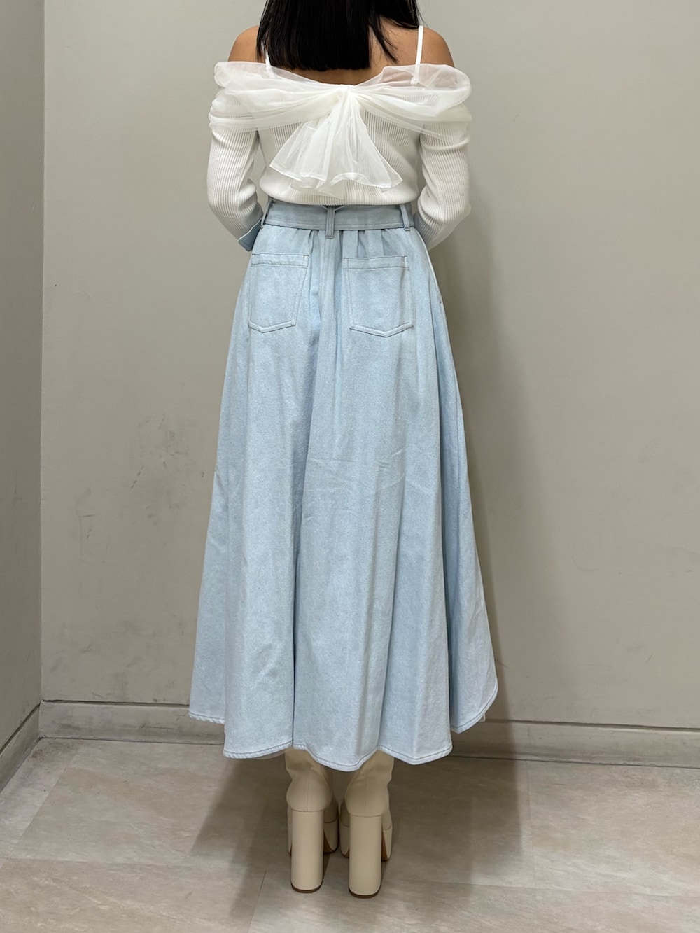 ホワイト系のニット/セーター、ブルー系のスカート、ホワイト系のブーツを着用したレディースの春コーディネートの3枚目の写真