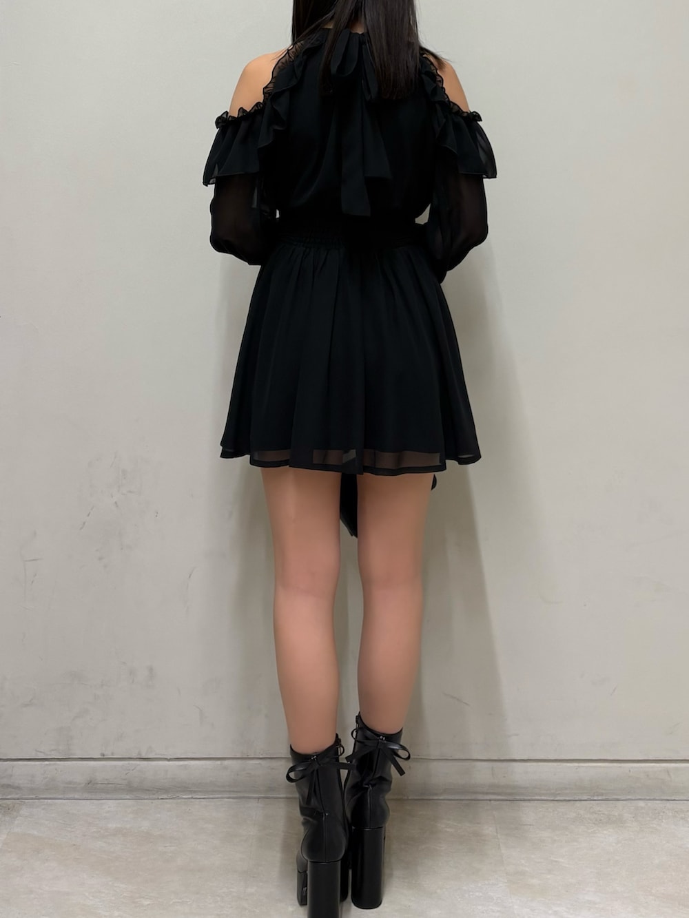 ブラック系のワンピース、ブラック系のブーツ、ブラック系のハンドバッグを着用したレディースの春コーディネートの3枚目の写真