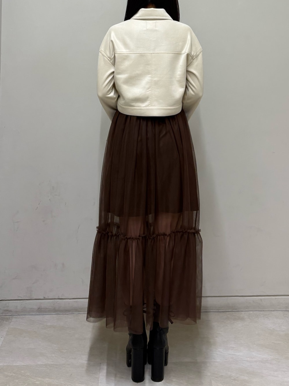 ホワイト系のブルゾン、ブラウン系のスカート、ブラック系のブーツを着用したレディースの春コーディネートの3枚目の写真