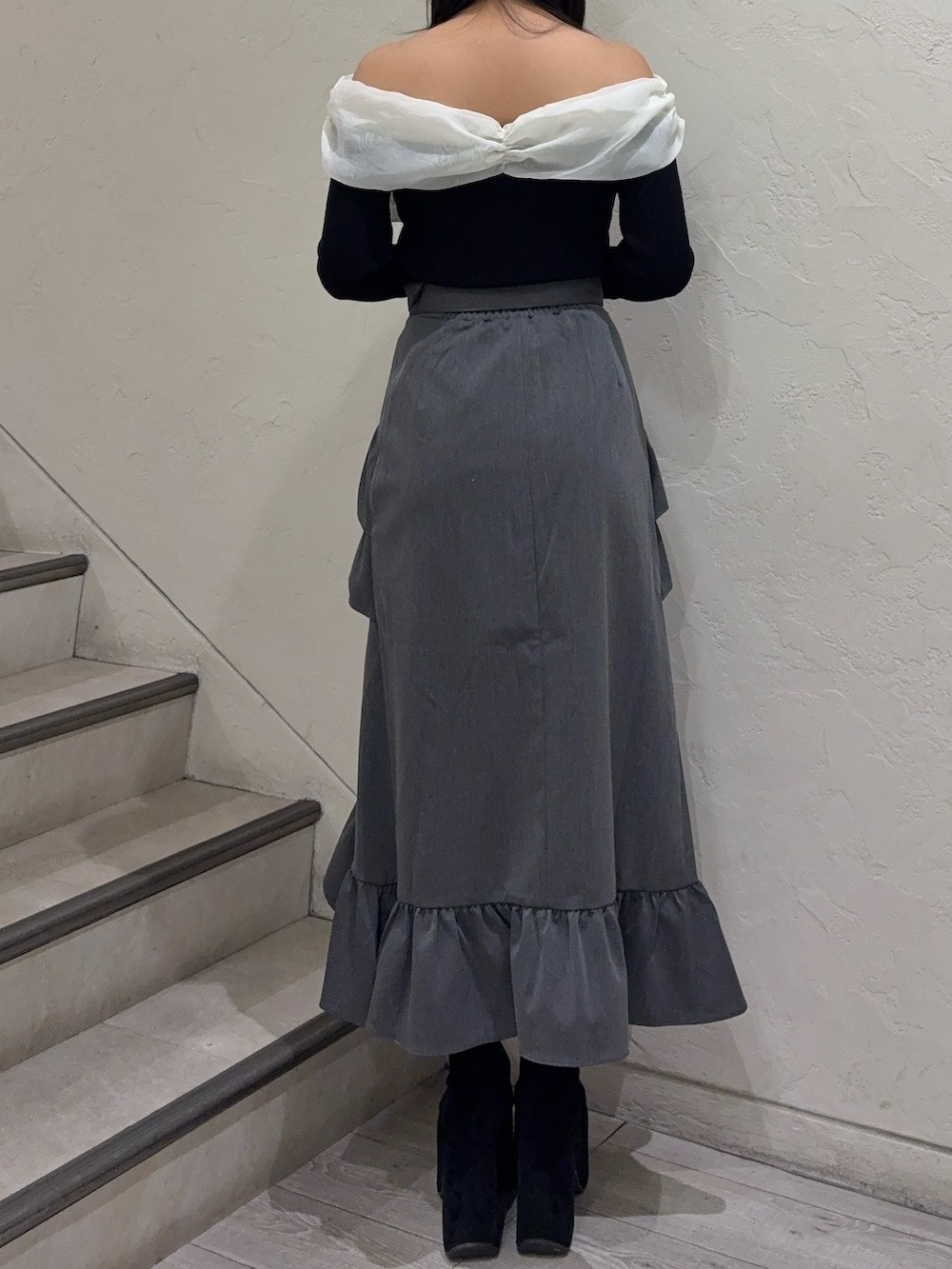 ブラック系のニット/セーター、グレー系のスカート、ブラック系のブーツを着用したレディースの春コーディネートの3枚目の写真