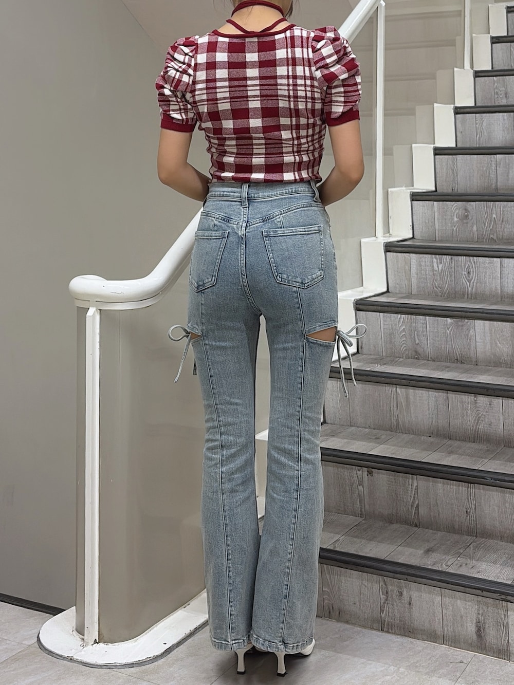 レッド系のニット/セーター、ブルー系のデニムパンツ、ホワイト系のサンダルを着用したレディースの夏コーディネートの3枚目の写真
