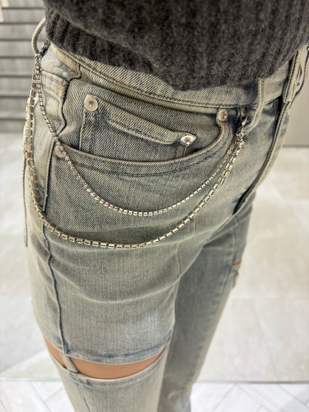 グレー系のニット/セーター、ブルー系のデニムパンツ、ホワイト系のサンダルを着用したレディースの夏コーディネートの4枚目の写真