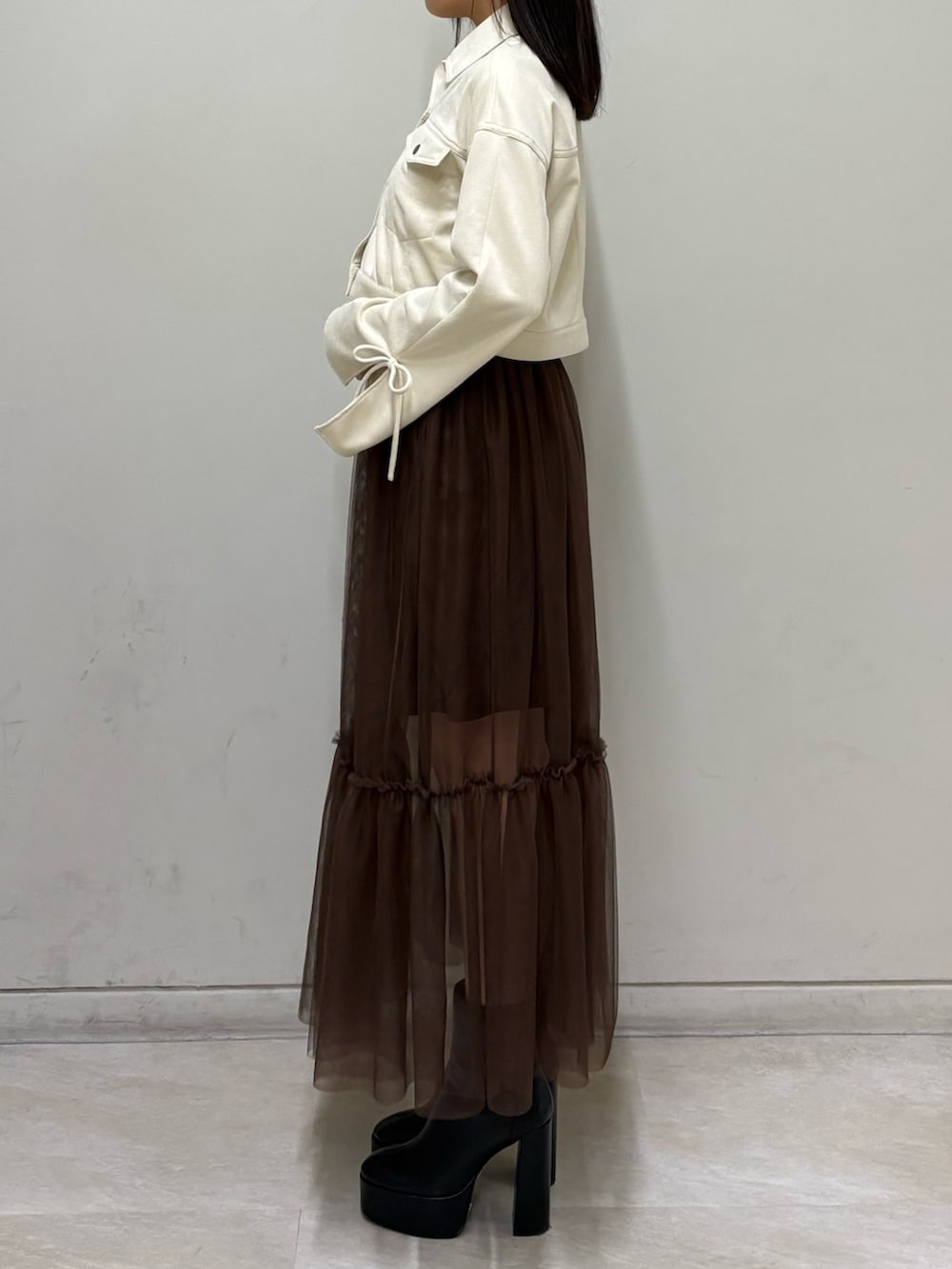 ホワイト系のブルゾン、ブラウン系のスカート、ブラック系のブーツを着用したレディースの春コーディネートの2枚目の写真