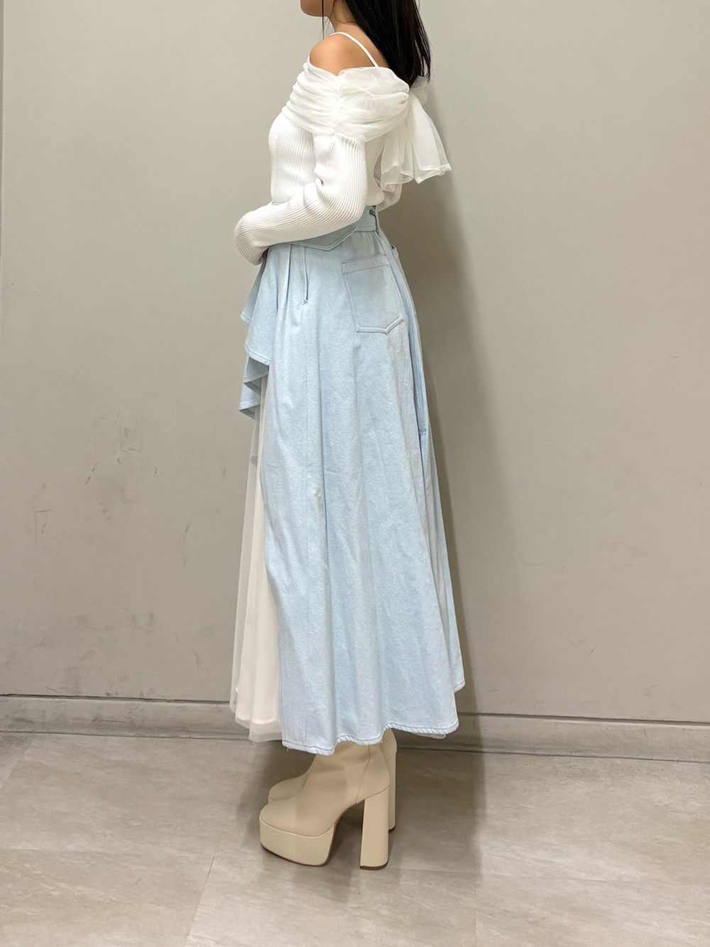ホワイト系のニット/セーター、ブルー系のスカート、ホワイト系のブーツを着用したレディースの春コーディネートの2枚目の写真